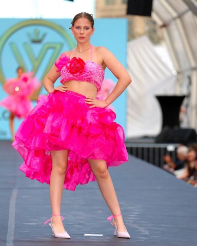 Model auf dem Laufsteg in einem pinken, voluminösen Kleid mit Blumendetail.